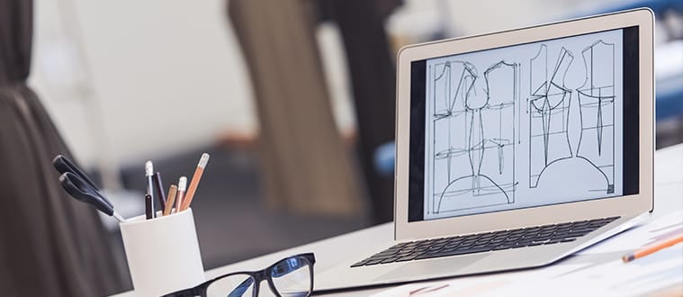 Bureau d'études textile avec des croquis sur un ordinateur et des mannequins pour le patronage vêtement