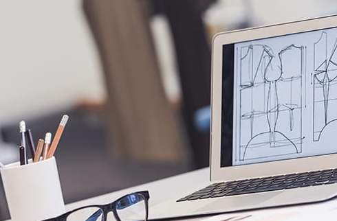 Bureau d'études textile avec des croquis sur un ordinateur et des mannequins pour le patronage vêtement